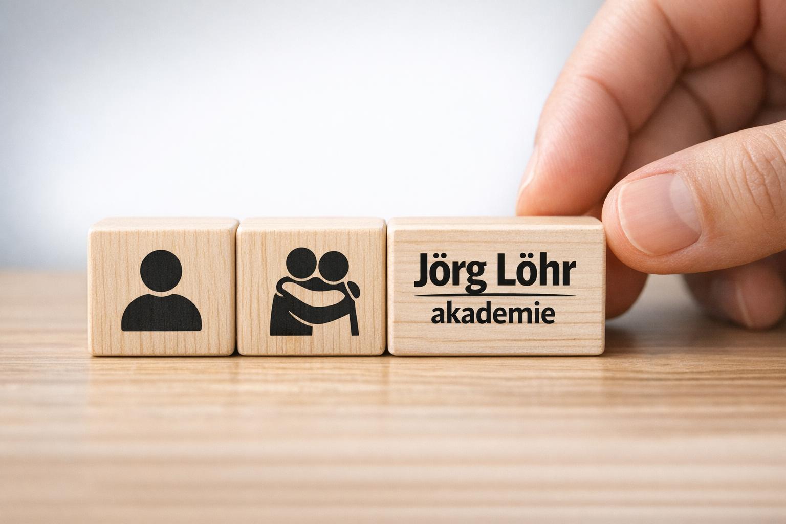The image shows a closeup of a hand arranging wooden blocks with icons representing different person icons one person 2 persons hugging The hand is in-Feb-05-2026-01-27-07-4552-PM